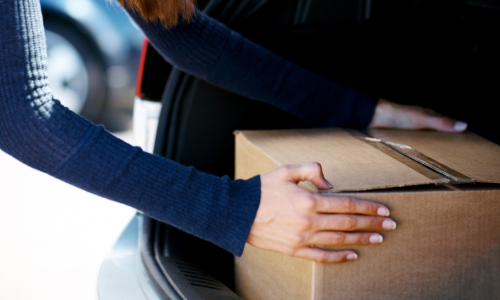 Woman putting a box in trunk